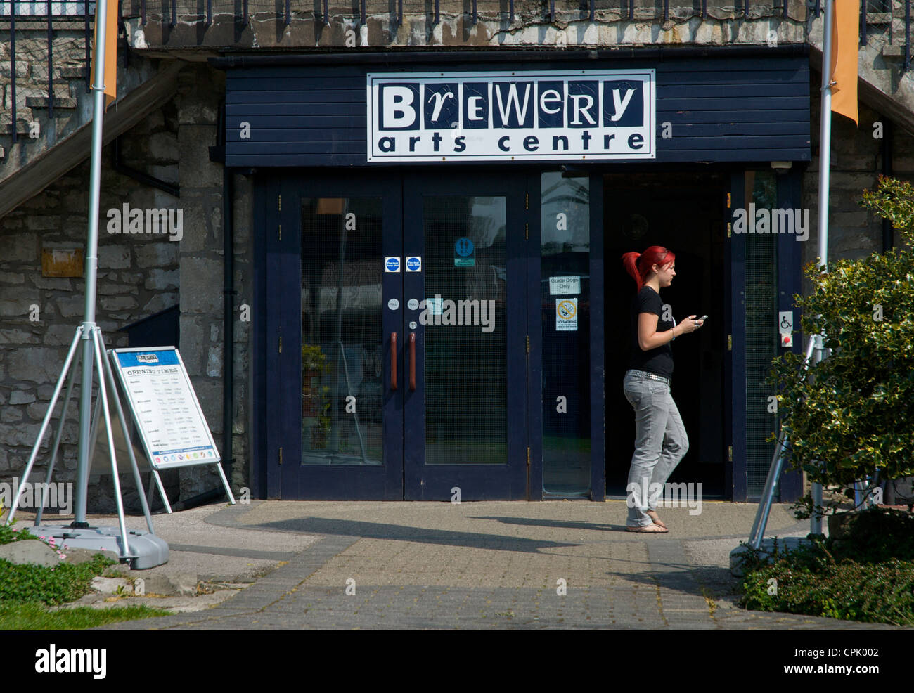 Young woman walking past the entrance of the Old Brewery Arts Centre, Kendal, Cumbria, England UK Stock Photo
