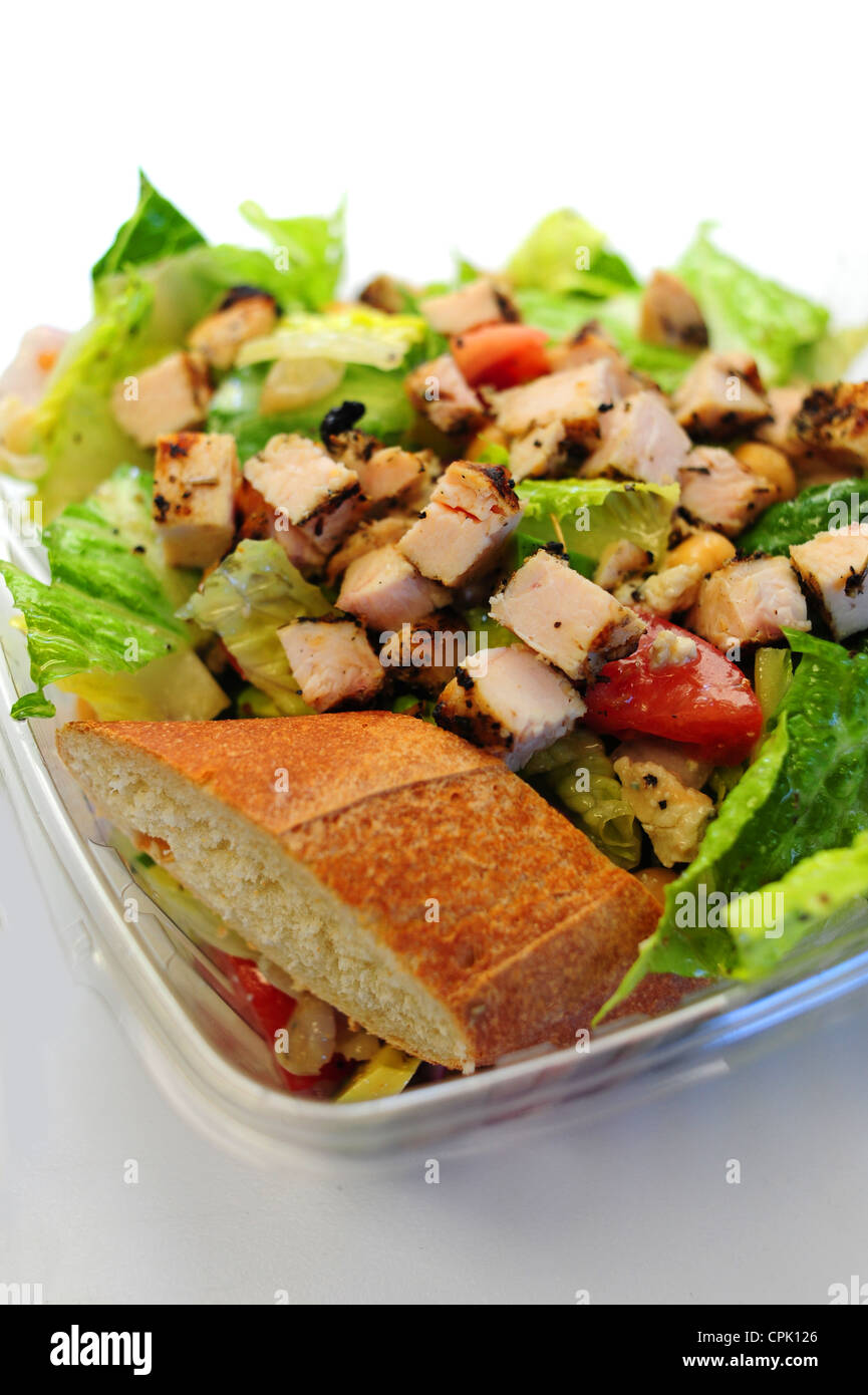 Foods a green salad with grilled chicken on top with a slice of baguette bread Stock Photo