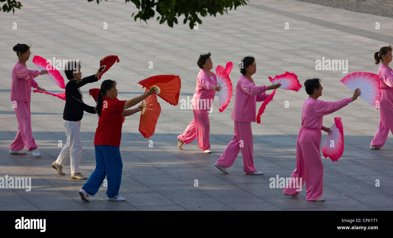 People practicing Taiji with red fans on the Bund in the morning, Shanghai, China Stock Photo