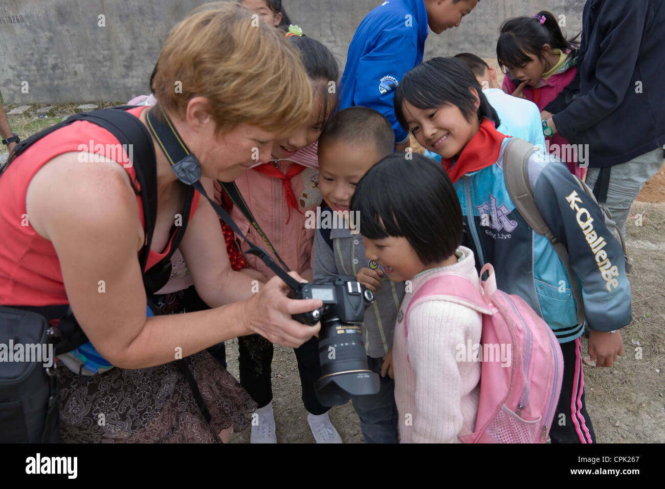 Tourist showing photos on digital camera to local children, Fujian, China Stock Photo