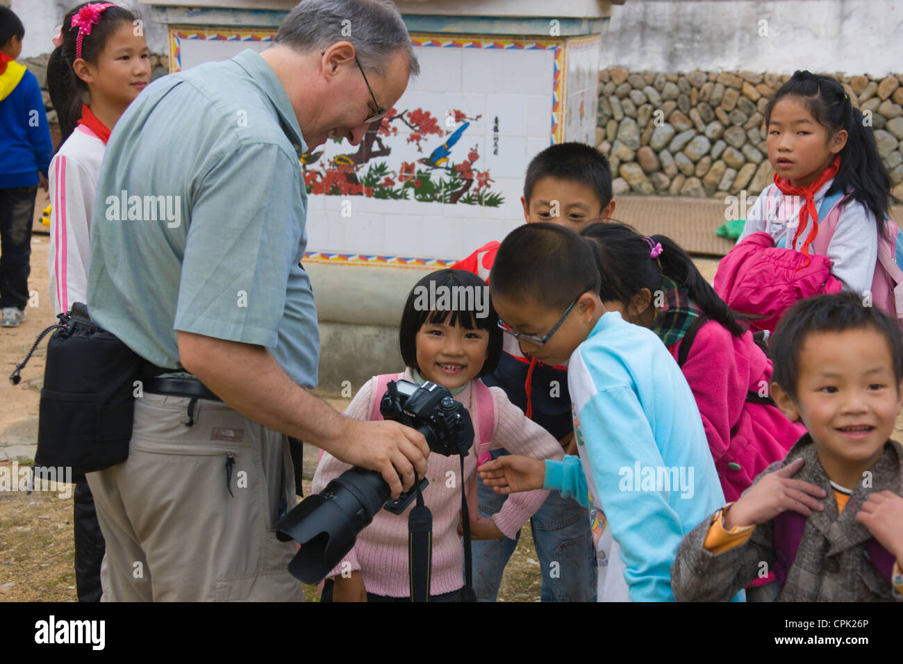 Tourist showing photos on digital camera to local children, Fujian, China Stock Photo