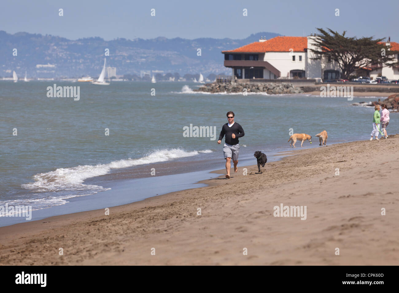 A man running on the beach with a dog Stock Photo