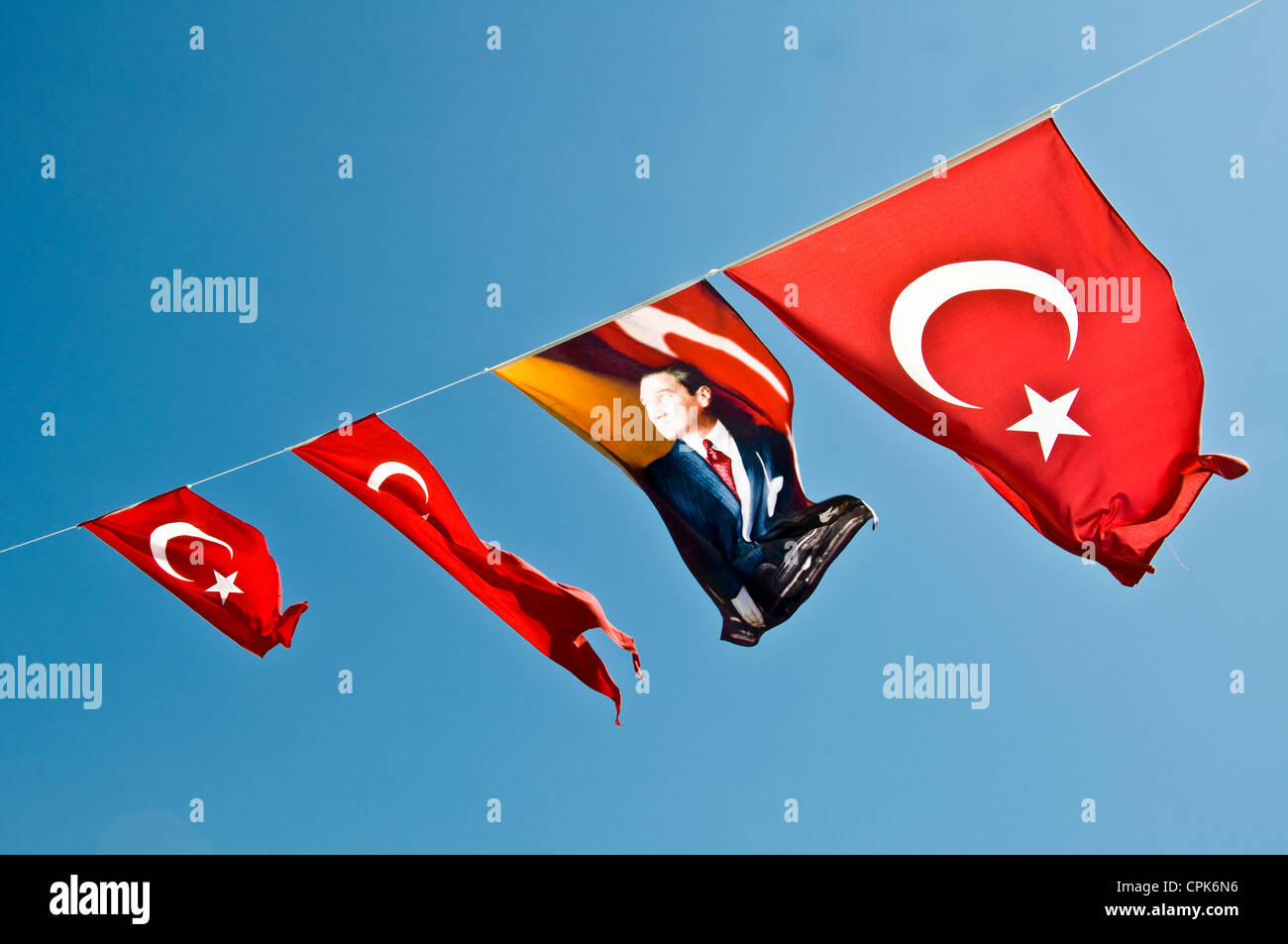 Four turkish flags against blue sky, one of them with a portrait of Mustafa Kemal Atatürk  - Istanbul, Turkey Stock Photo