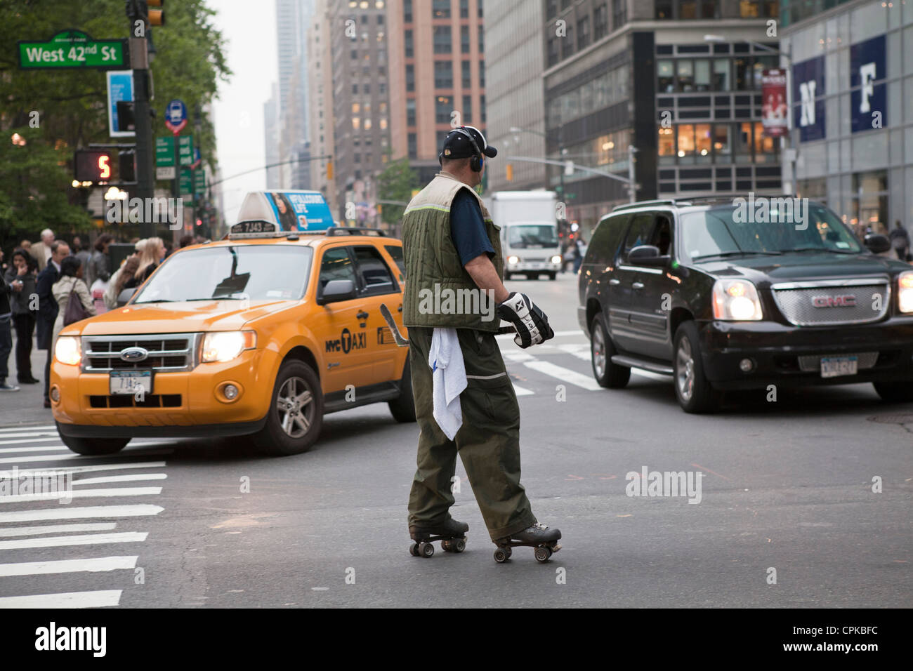 A man wearing hockey gear roller skates in the street in New York City