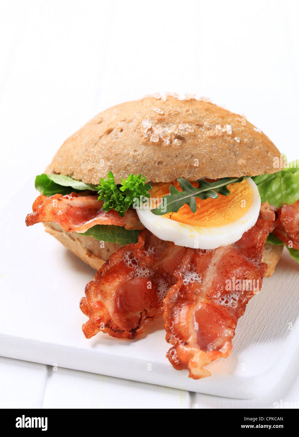 Bread bun with strips of crispy bacon Stock Photo