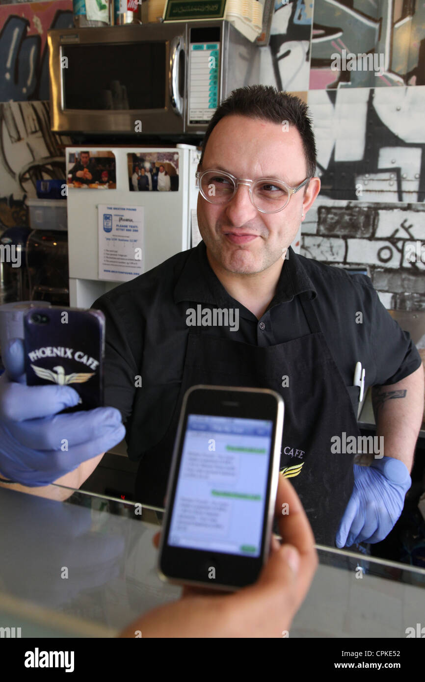 Purchasing an item in a cafe by smart phone, a system which is in use through the Brixton Pound, an alternative currency. Stock Photo