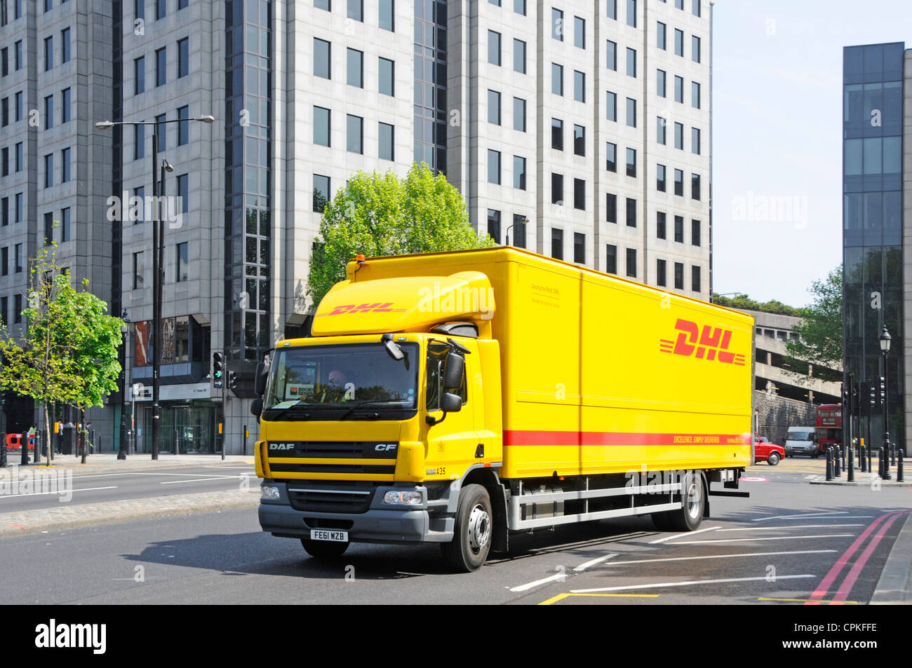 Yellow DHL Deutsche Post delivery lorry truck driver driving along street in Tower Hill in Tower Hamlets Borough East London England UK Stock Photo