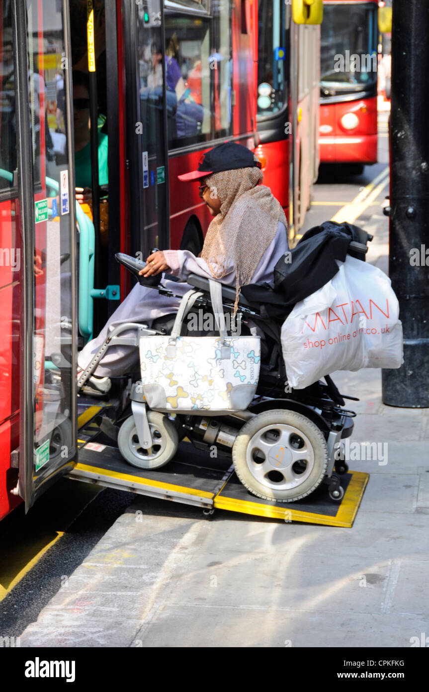 Passenger boarding double decker bus on wheelchair ramp from pavement to enter  transport for London service Oxford Street West End London England UK Stock Photo