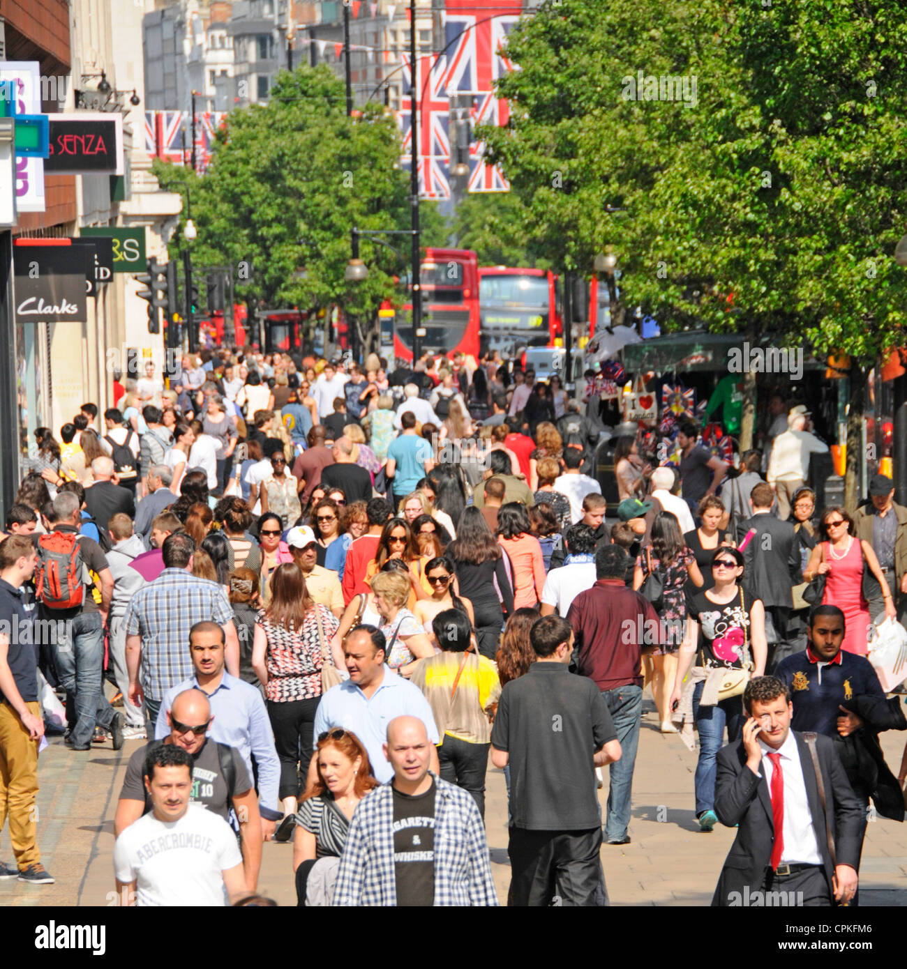 Busy Oxford Street crowd of shoppers & tourists view from above walking on pavement West End retail shopping street & shop fronts summer day London UK Stock Photo