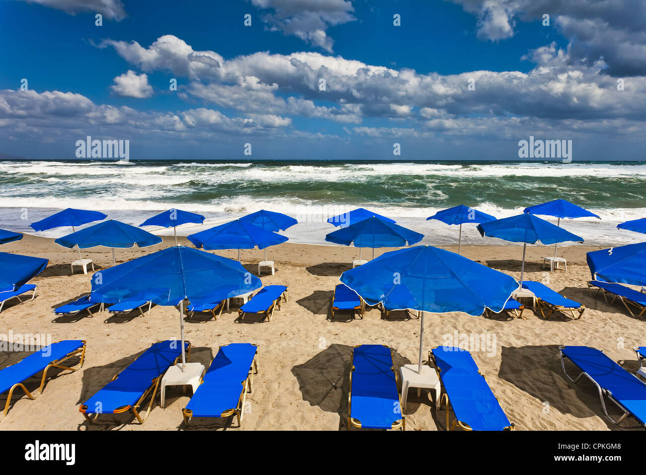 Blue parasols at an empty, stormy beach in Platania, Crete Stock Photo