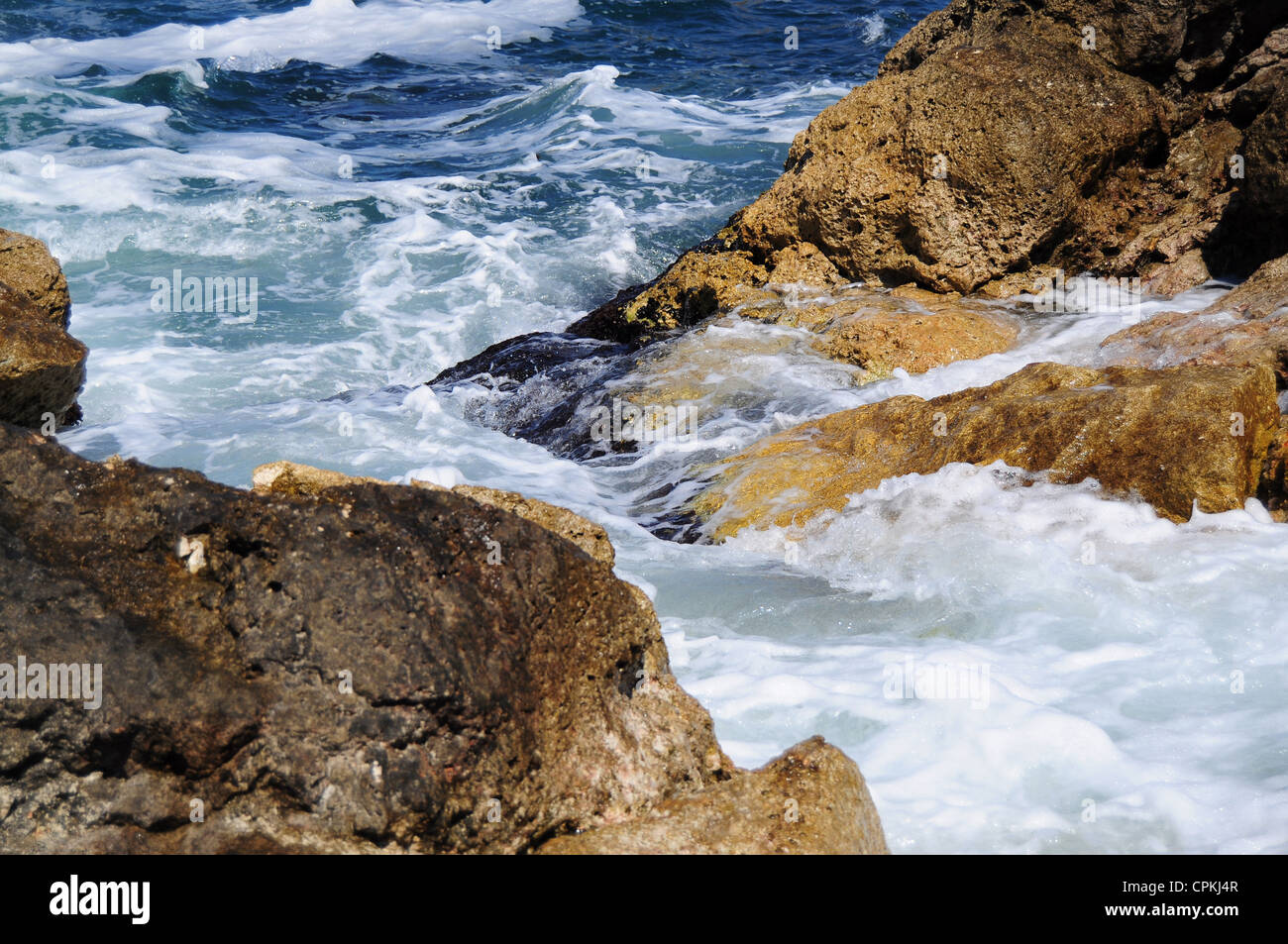 Waves splashing into rocks at sea Stock Photo
