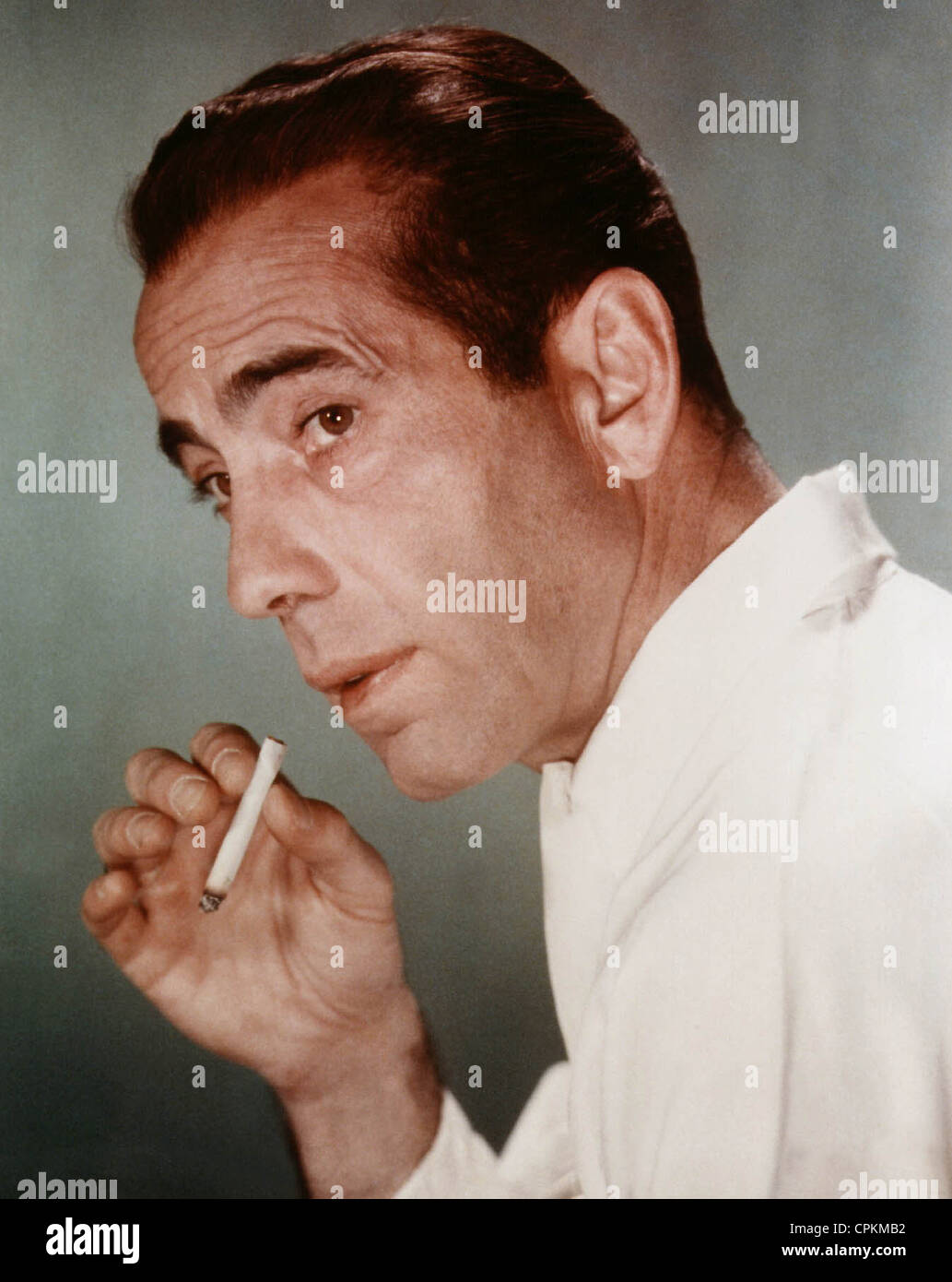 A color portrait of the film star Humphrey Bogart taken in Los Angeles in 1950. He is smoking a cigarette. Stock Photo