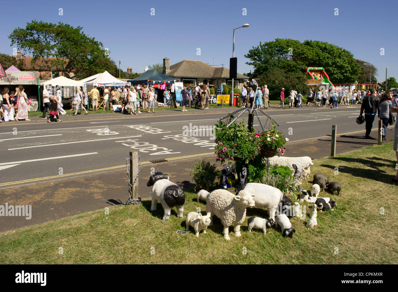 Sculptures of sheep and farmyard animals set on grass under a 4-arm hanging basket roadside at Yarmouth Old Gaffers Festival, Isle of Wight, 2012. Stock Photo