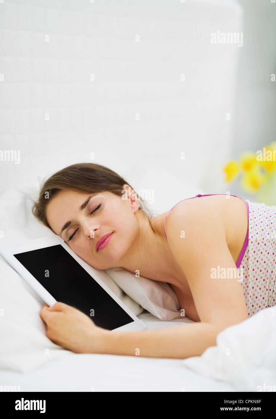 Happy girl sleeping embracing tablet PC Stock Photo