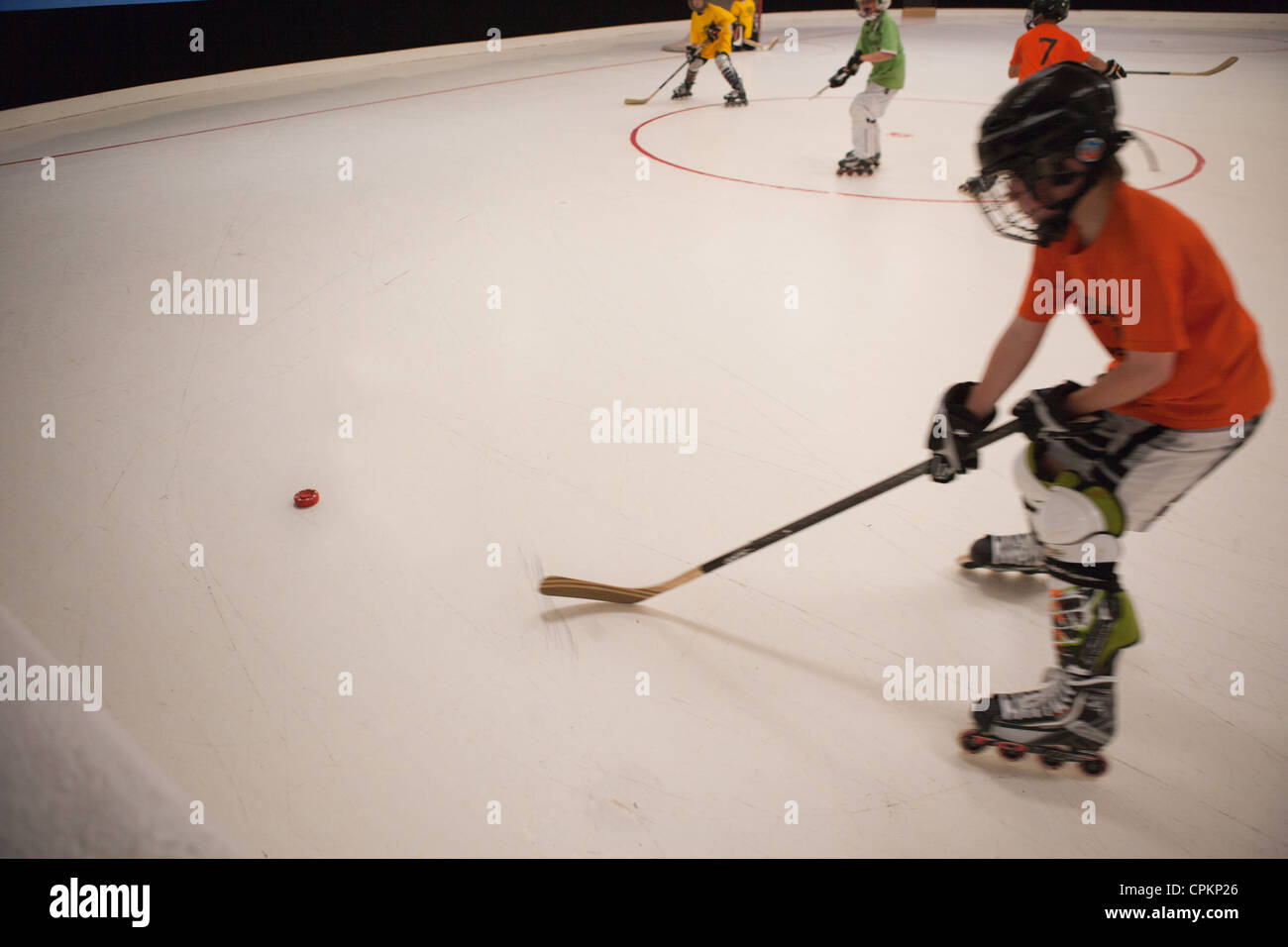 Hockey player skating in rink, youth hockey league, aiming for puck