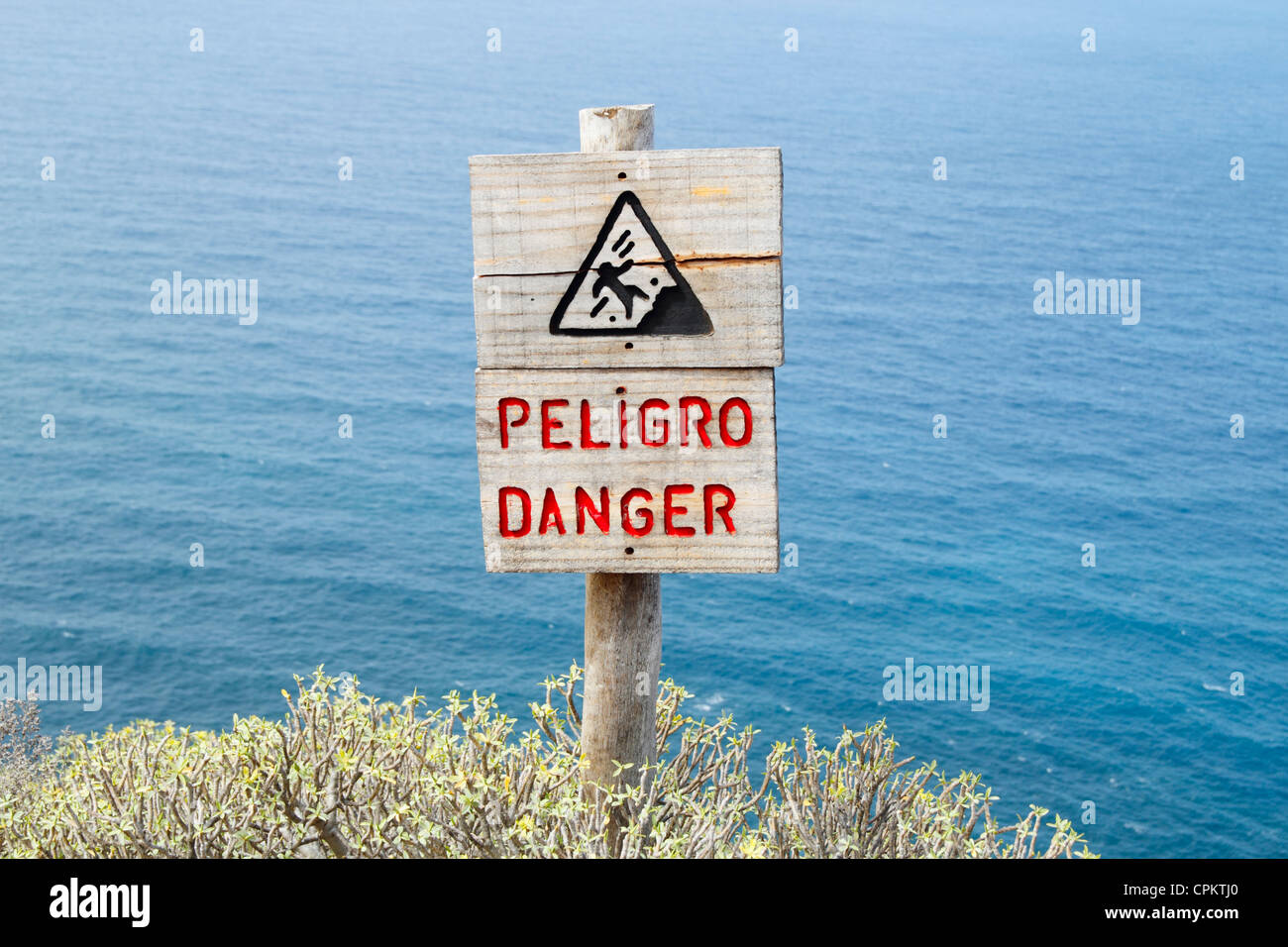 Danger sign in English and Spanish on high coastal footpath in Spain