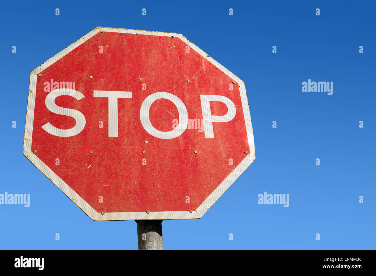 Dirty old red British Stop sign and blue sky. Stock Photo