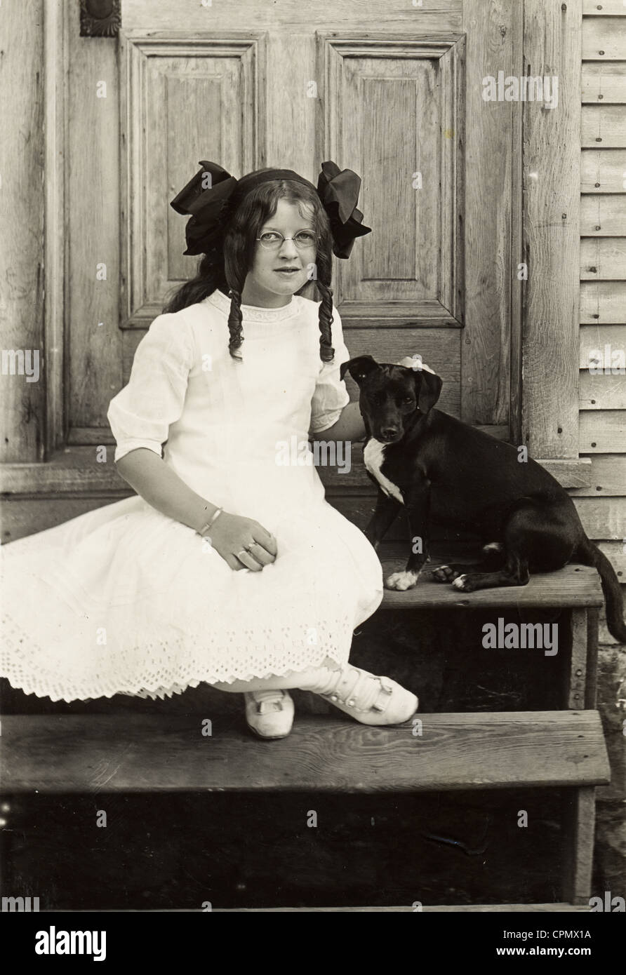Little Girl with Glasses Sitting with Small Black Dog Stock Photo