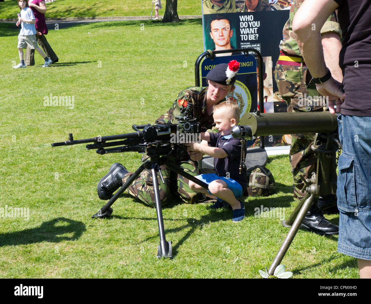 Female soldier demonstrating use of gun to child Stock Photo