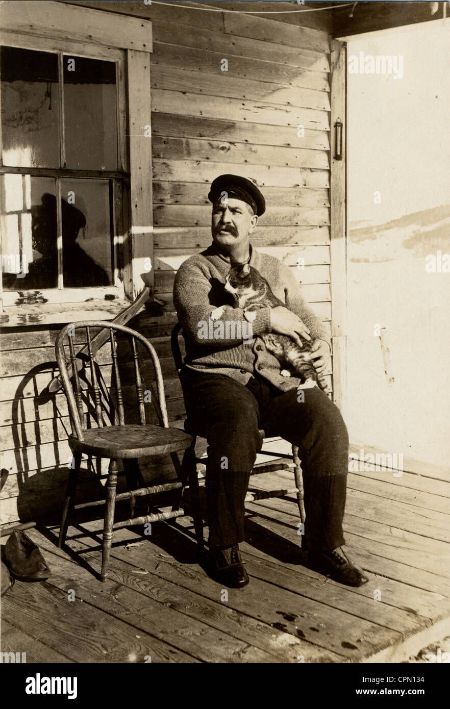 Older Man Cradling Tabby Cat on a Cabin Porch Stock Photo