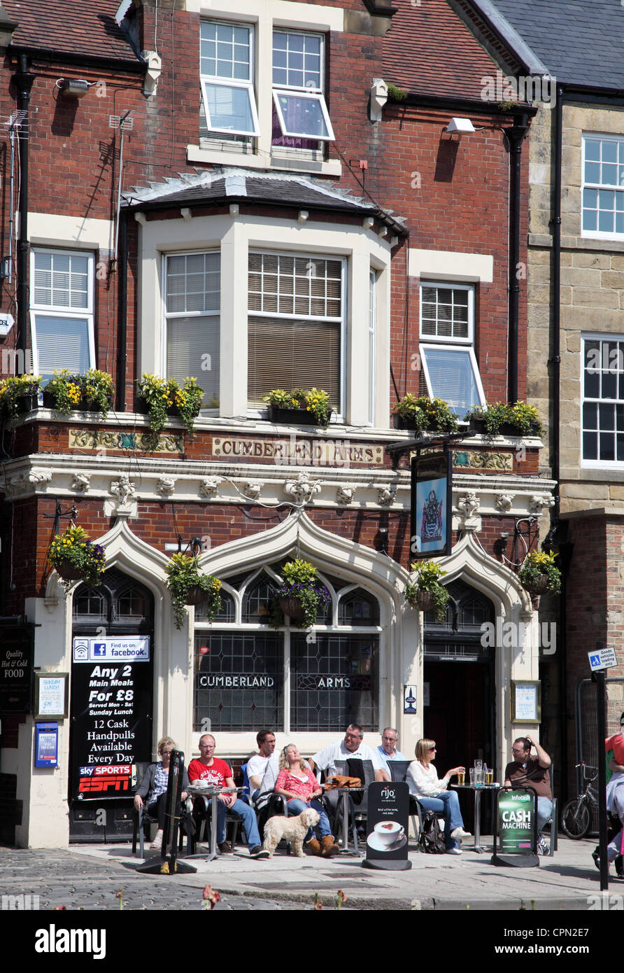People sitting drinking outside Cumberland Arms pub on Tynemouth High Street, North East England
