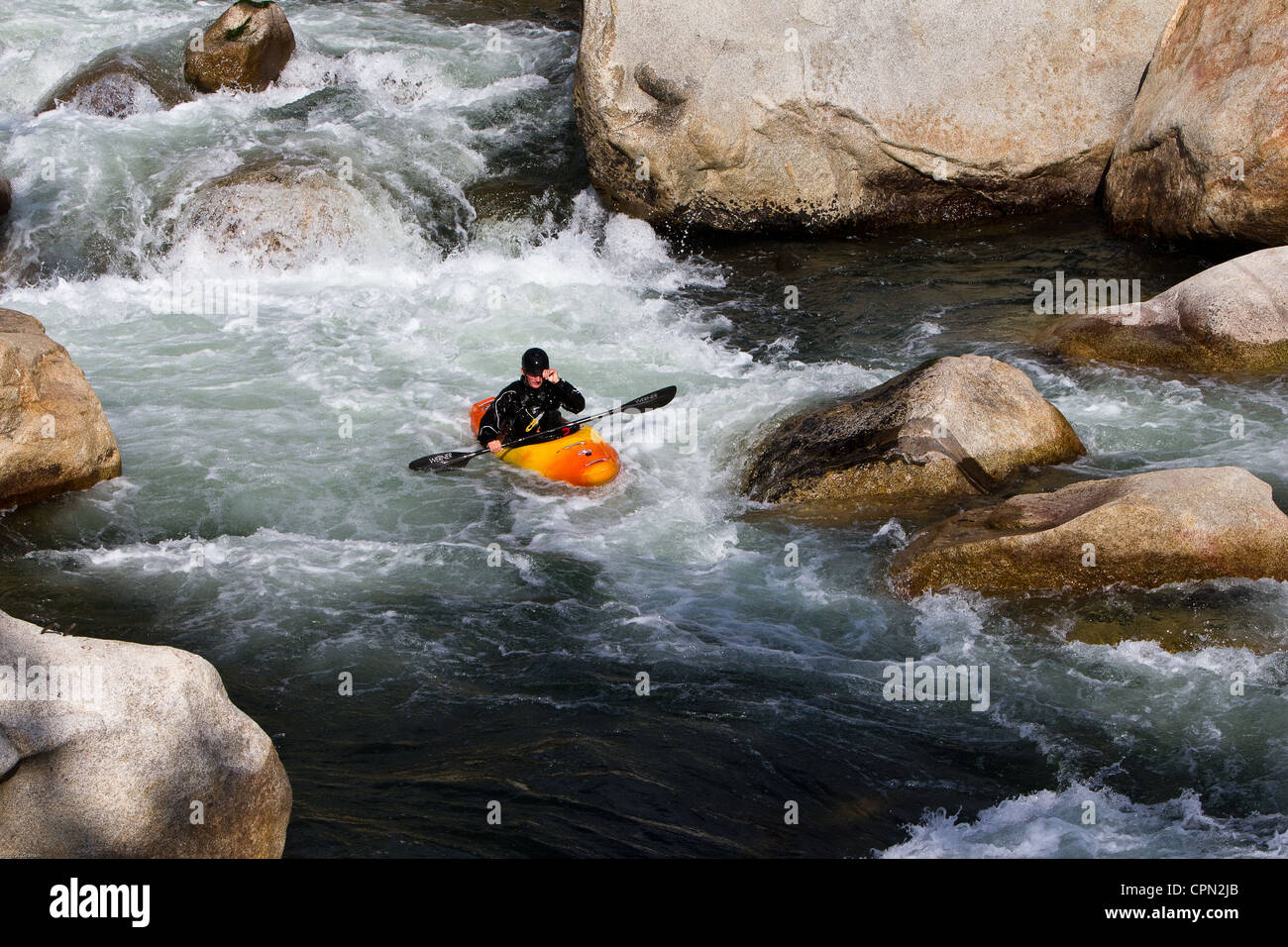 A whitewater rafter coming  down the river stops to make an adjustment... Stock Photo