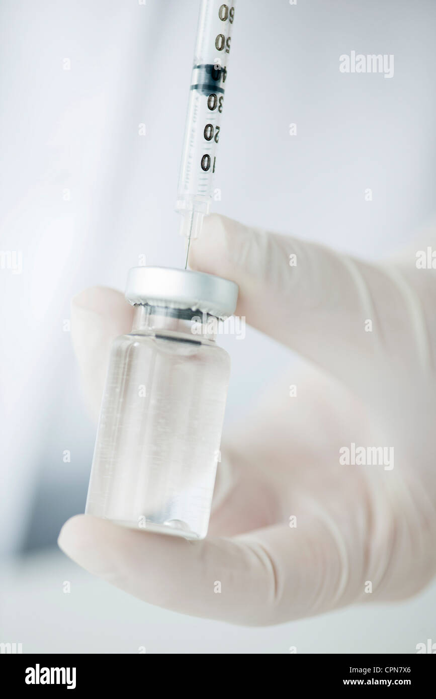 Extracting liquid from vial with syringe Stock Photo