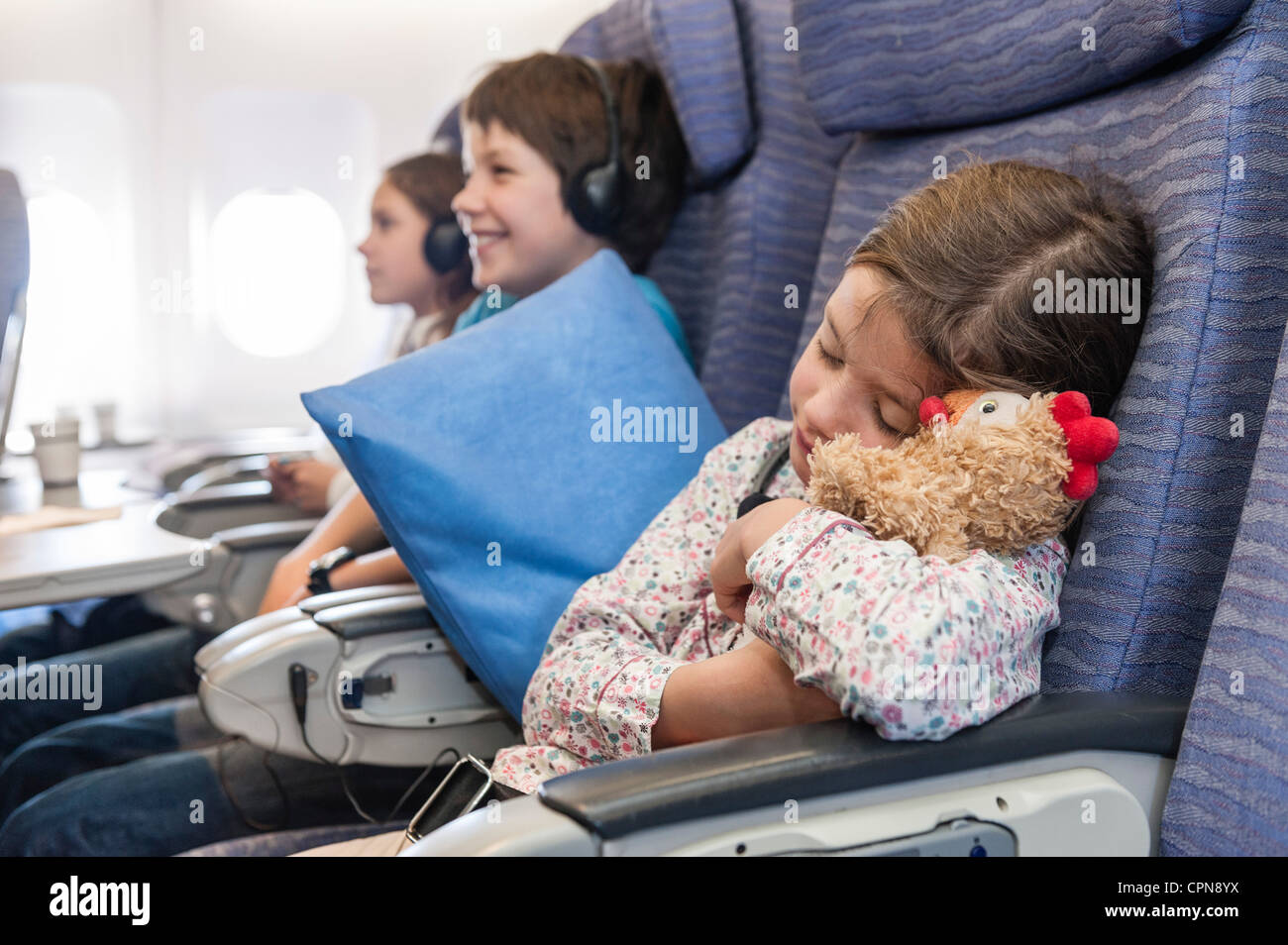 Girl sleeping on airplane holding stuffed animal Stock Photo Alamy
