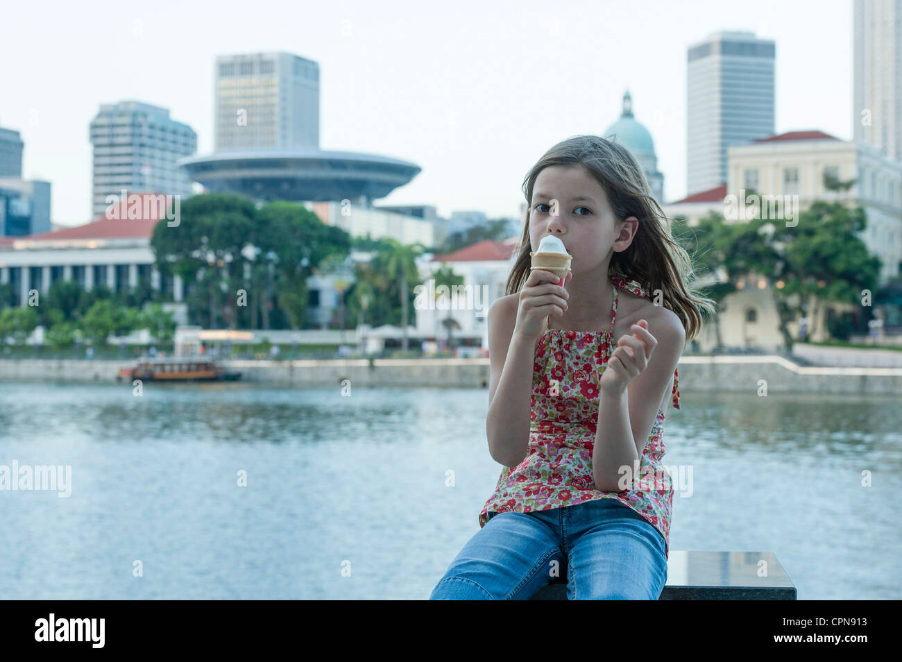 Girl eating ice cream cone by river Stock Photo