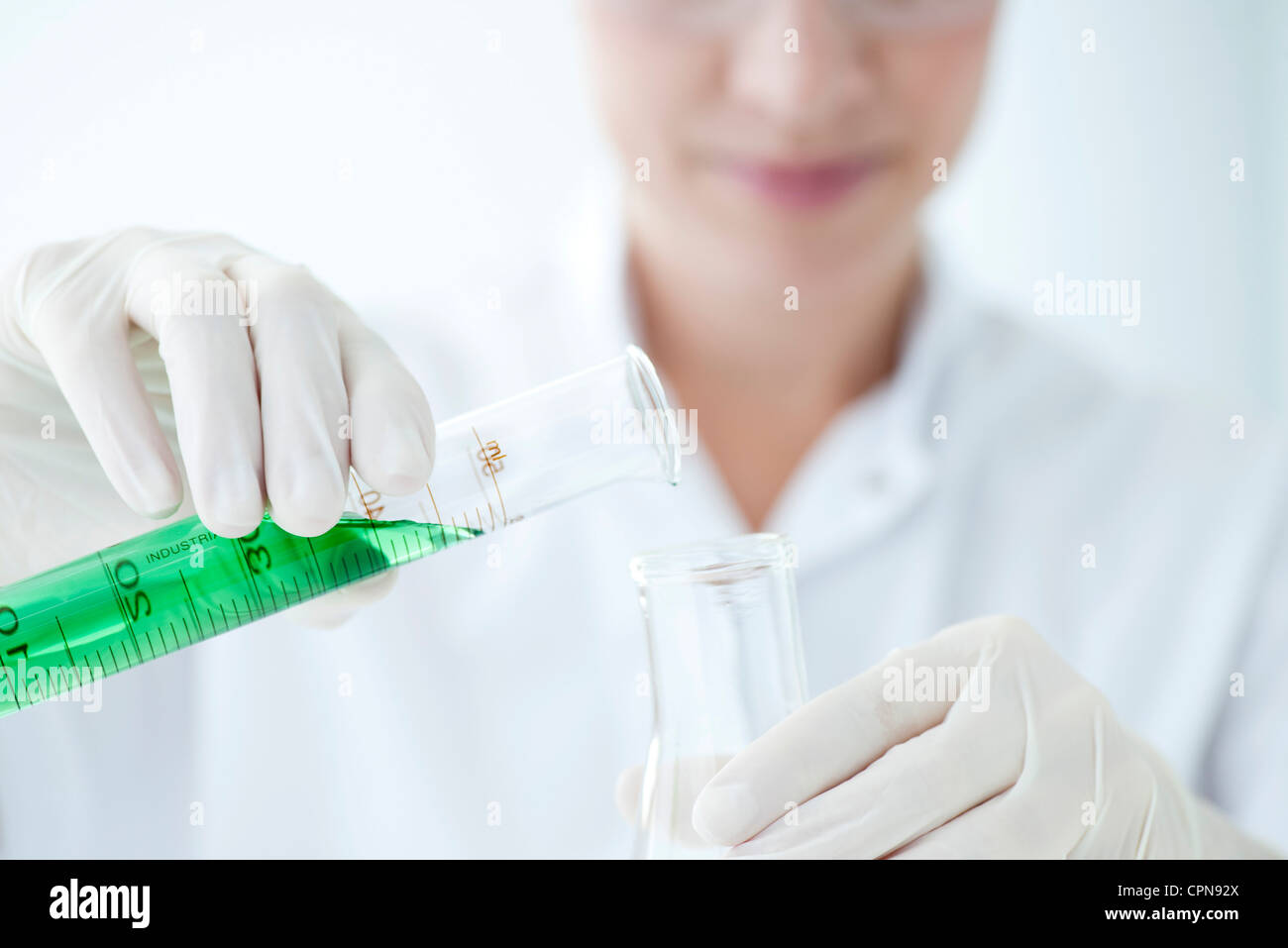 Scientist pouring liquid from graduated cylinder to test tube Stock Photo