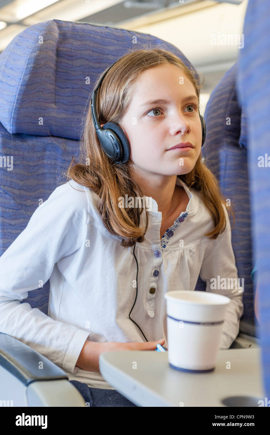 Girl watching movie with headphones on airplane Stock Photo Alamy