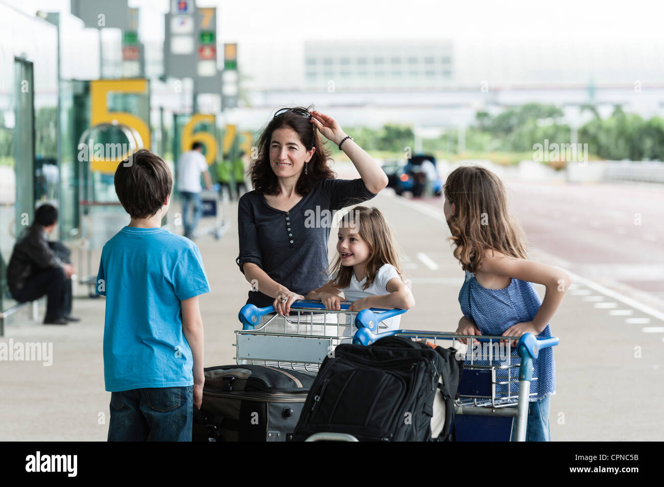 Family standing outside of airport with luggage Stock Photo - Alamy