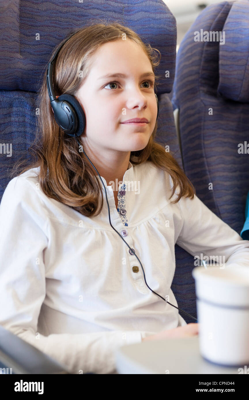 Girl watching movie with headphones on airplane Stock Photo Alamy