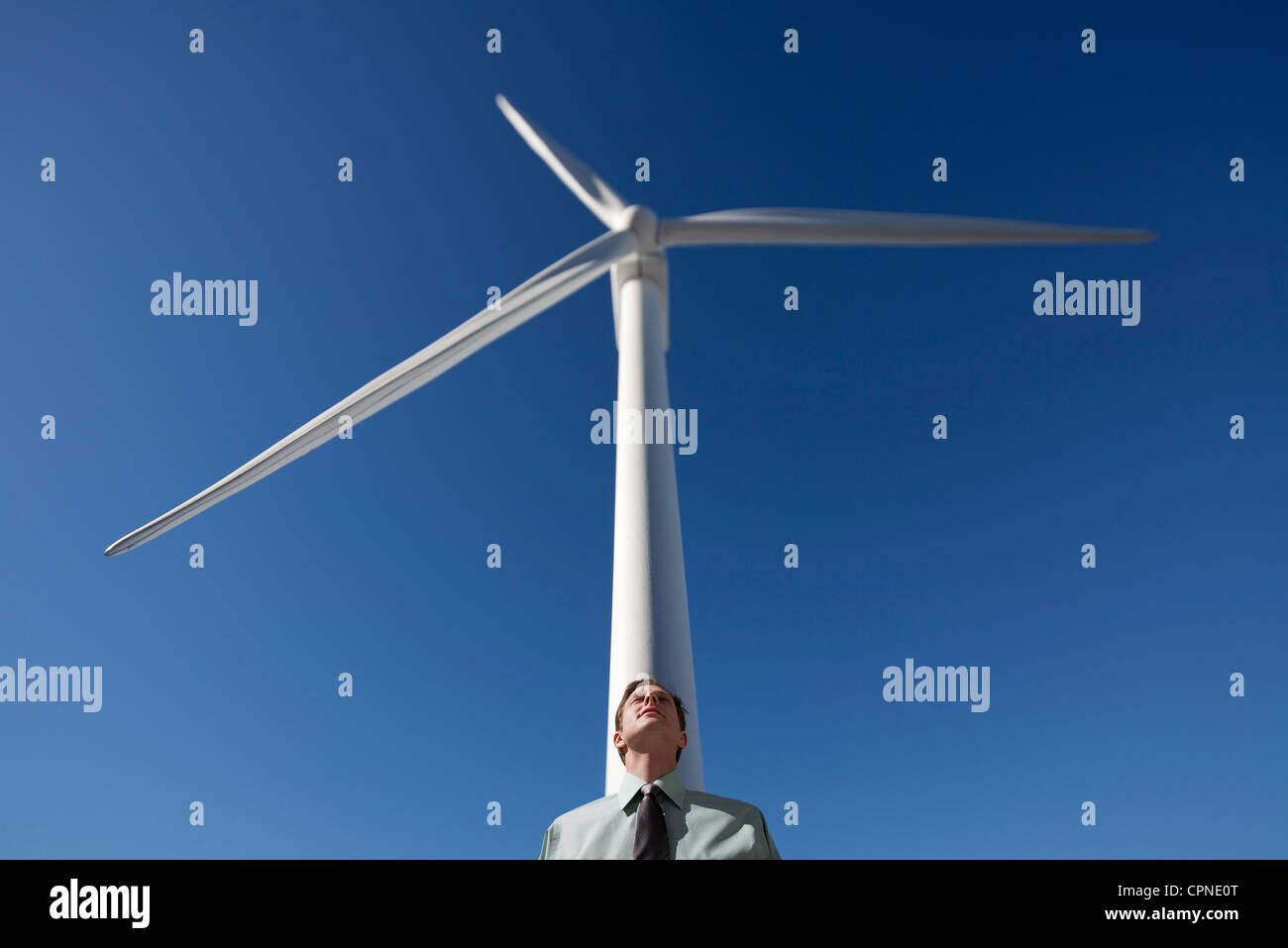 Businessman leaning against wind turbine Stock Photo Alamy