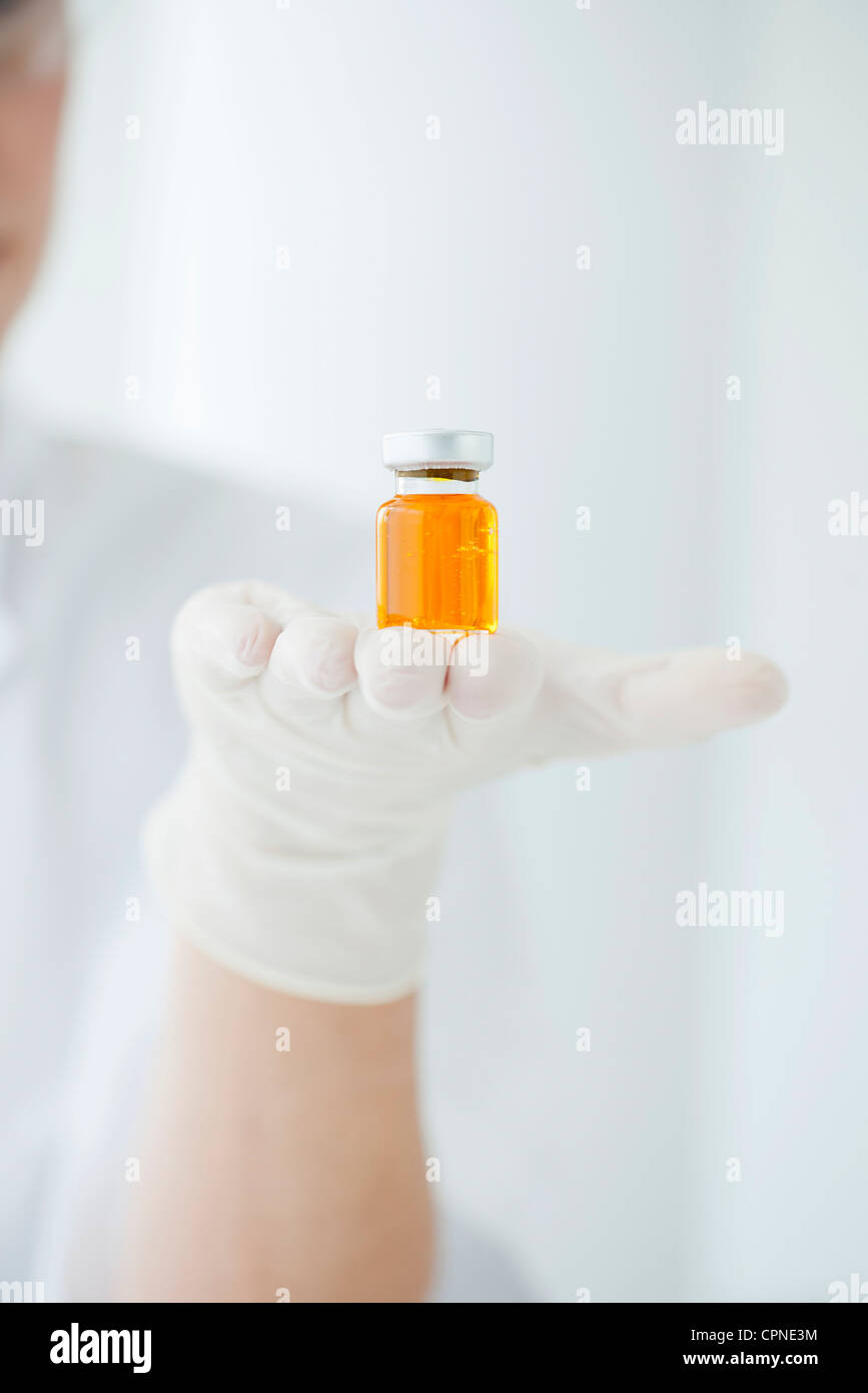 Scientist holding vial containing orange liquid Stock Photo Alamy
