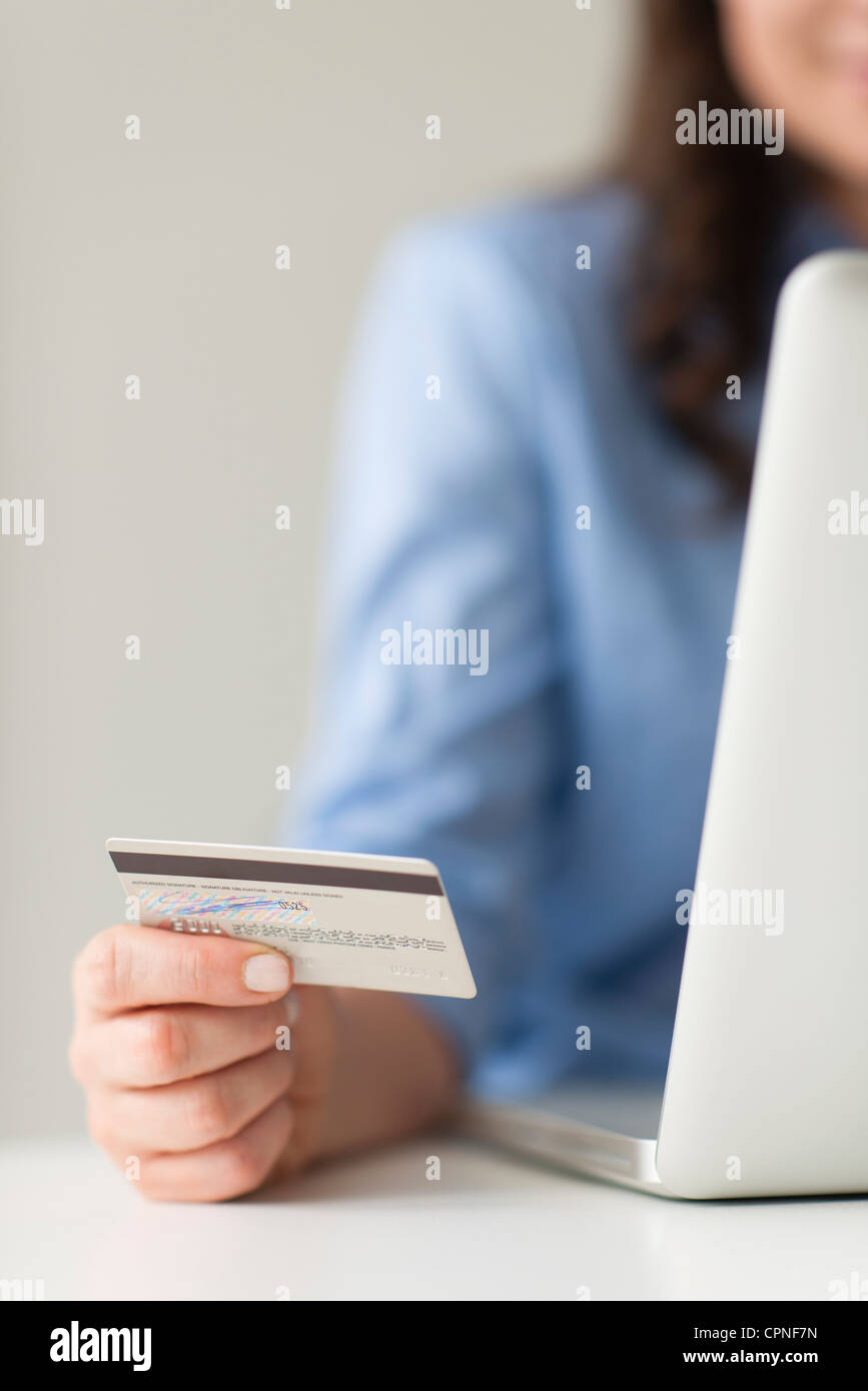 Woman holding credit card beside laptop computer Stock Photo