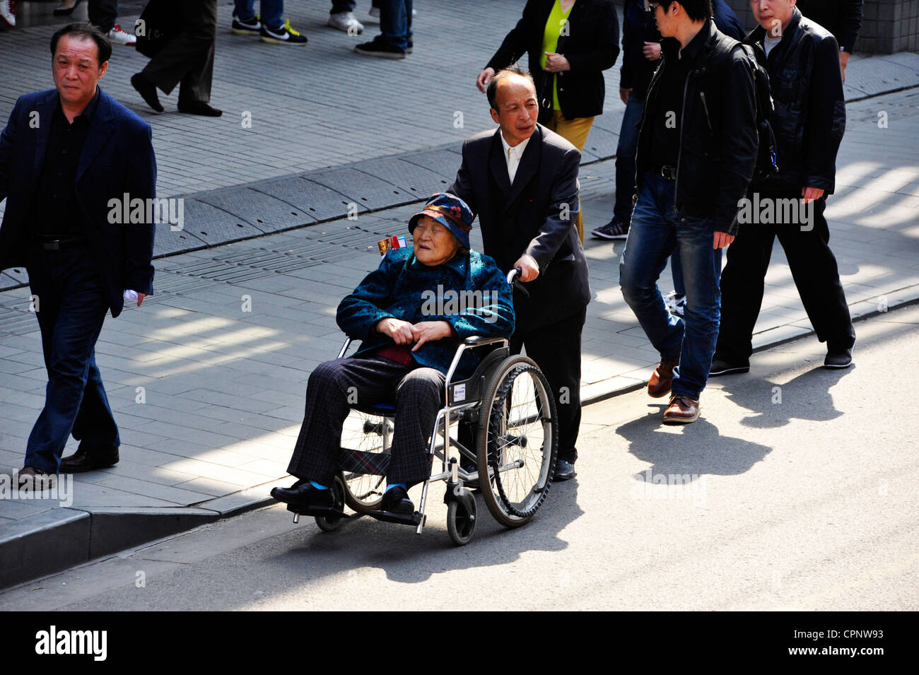 A disabled Chinese woman in a wheelchair in Shanghai. Stock Photo