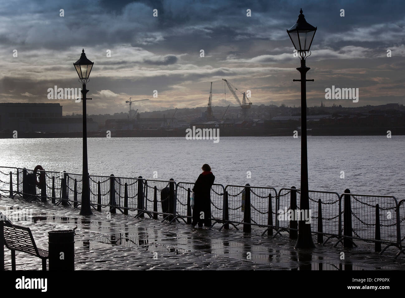 Liverpool Albert Docks pictured tourists gaze over the rails into the Mersey Stock Photo
