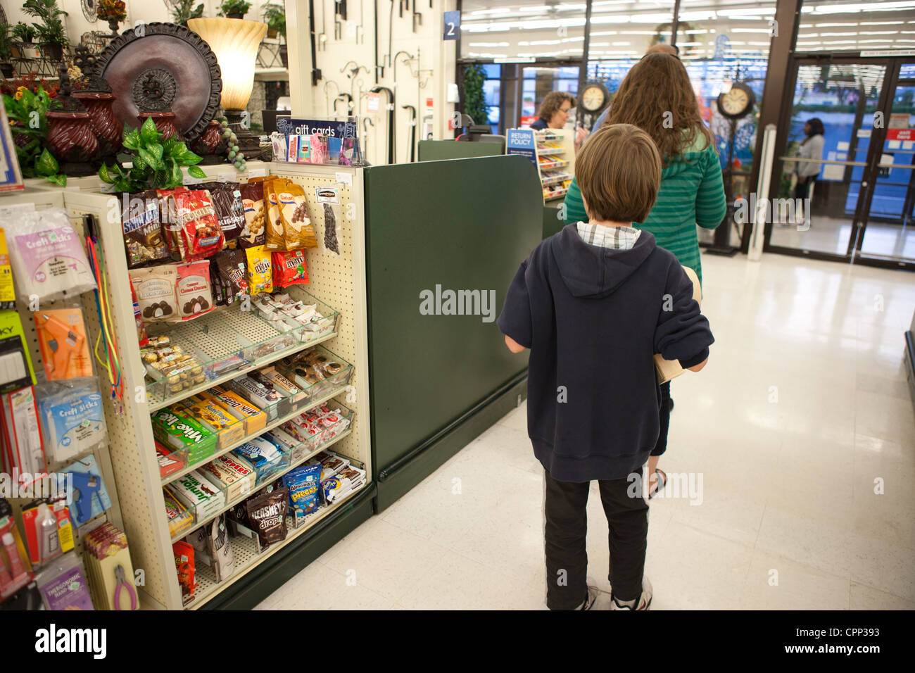 Nine year old getting ready to pay for an item in a store and looking at candy for sale in check out line. Stock Photo