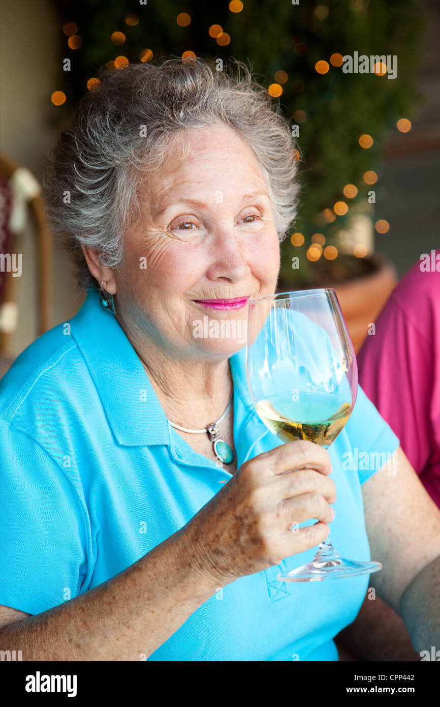 Senior woman enjoys the taste and aroma of a good glass of white wine ...