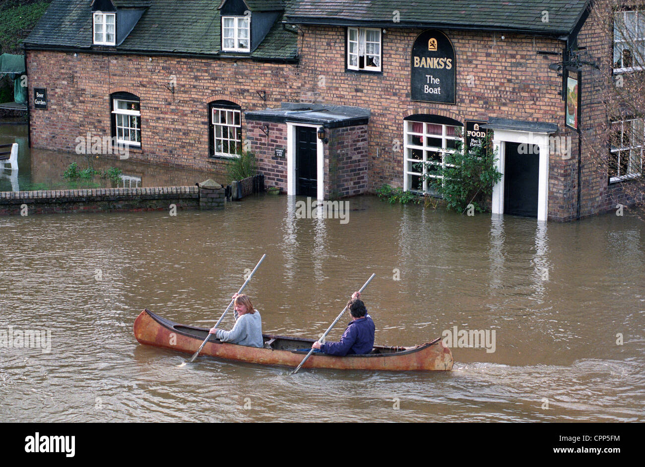 Couple in canoe on the River Severn in flood at the Boat Inn Jackfield