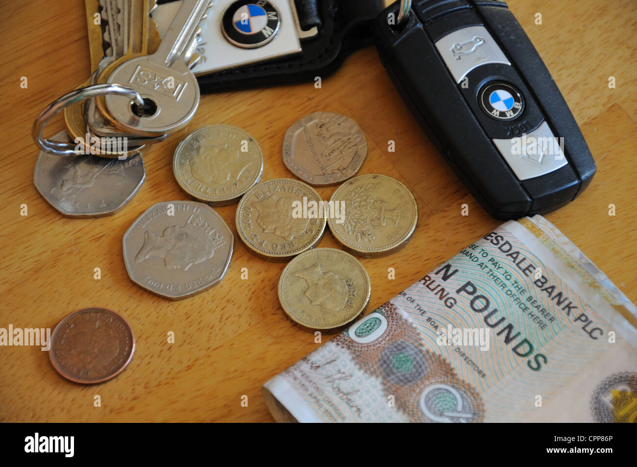 House keys, car keys, notes and loose change on table top. Stock Photo