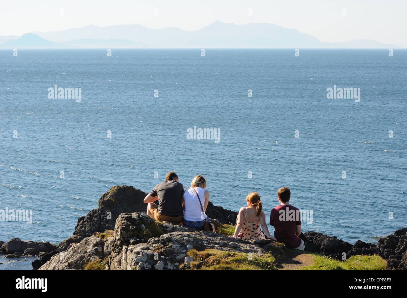 Two girls and two boys gaze out over the Firth of Clyde on a sunny day in Ayrshire, Scotland, UK Stock Photo