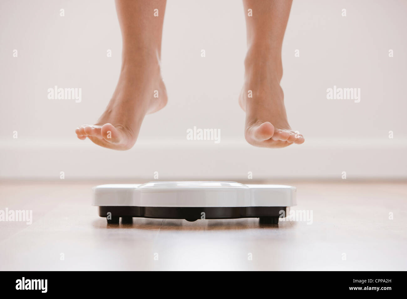 Caucasian woman's feet jumping on scale Stock Photo
