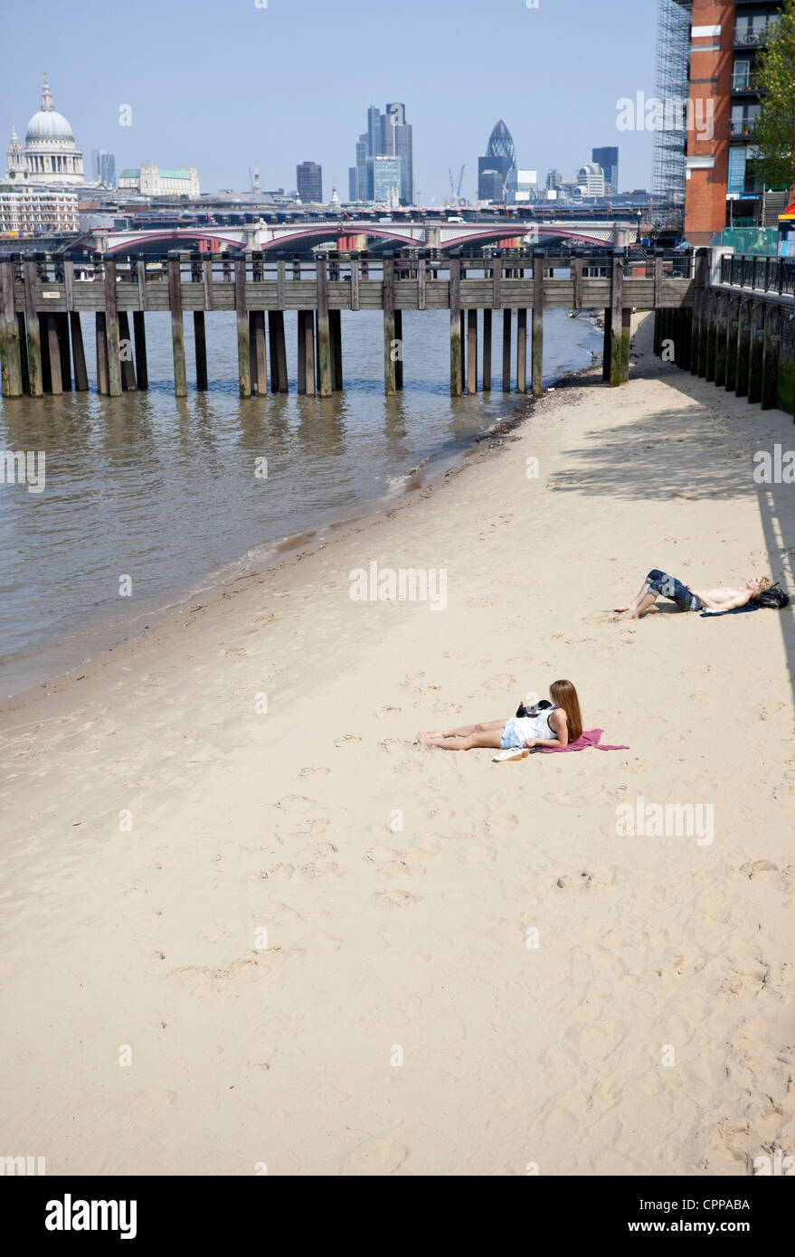 Sunbathers on a sandy beach by River Thames, Southbank, London, England, UK Stock Photo