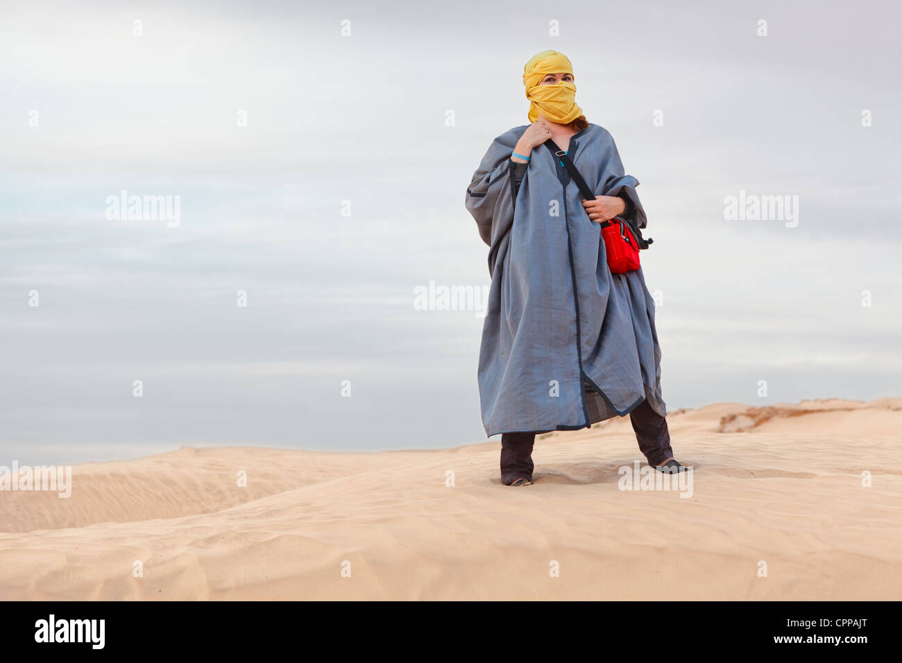 Woman in Bedouin clothes standing on dune in desert. Sahara desert, Tunisia. Horizontal Stock Photo