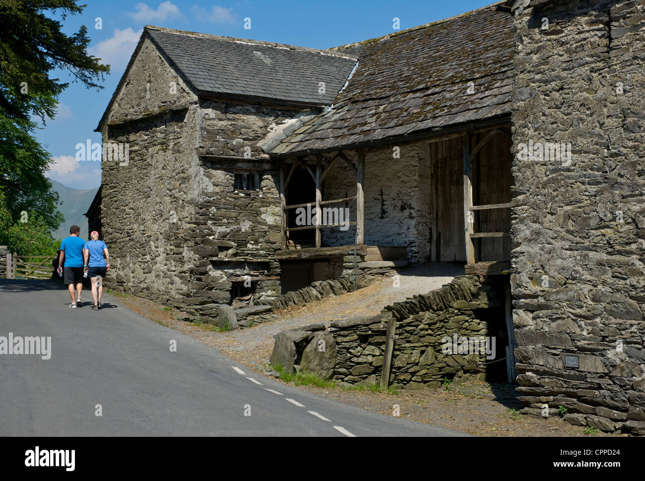 Two walkers passing Townend Barn, in the village of Troutbeck, Lake District National Park, Cumbria UK Stock Photo