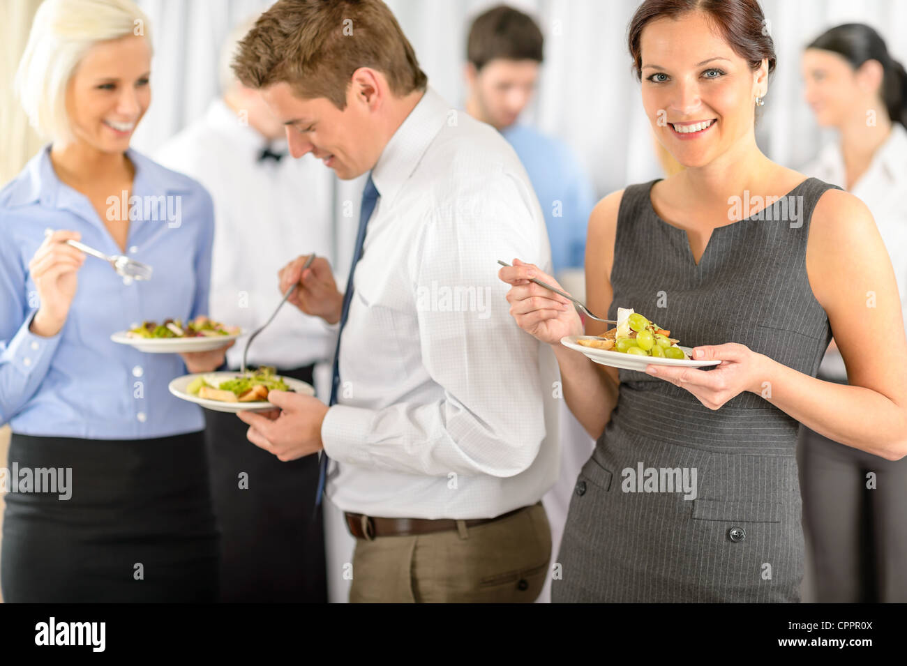 Smiling business woman during company lunch buffet hold salad plate Stock Photo