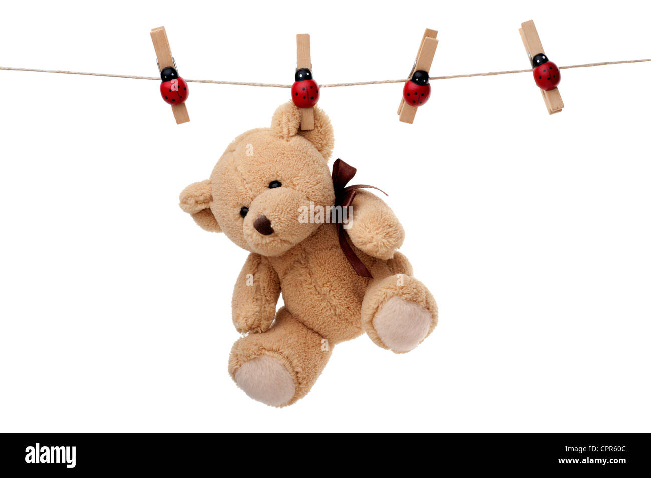 Small teddy bear hanging on clothesline, isolated on white background Stock Photo