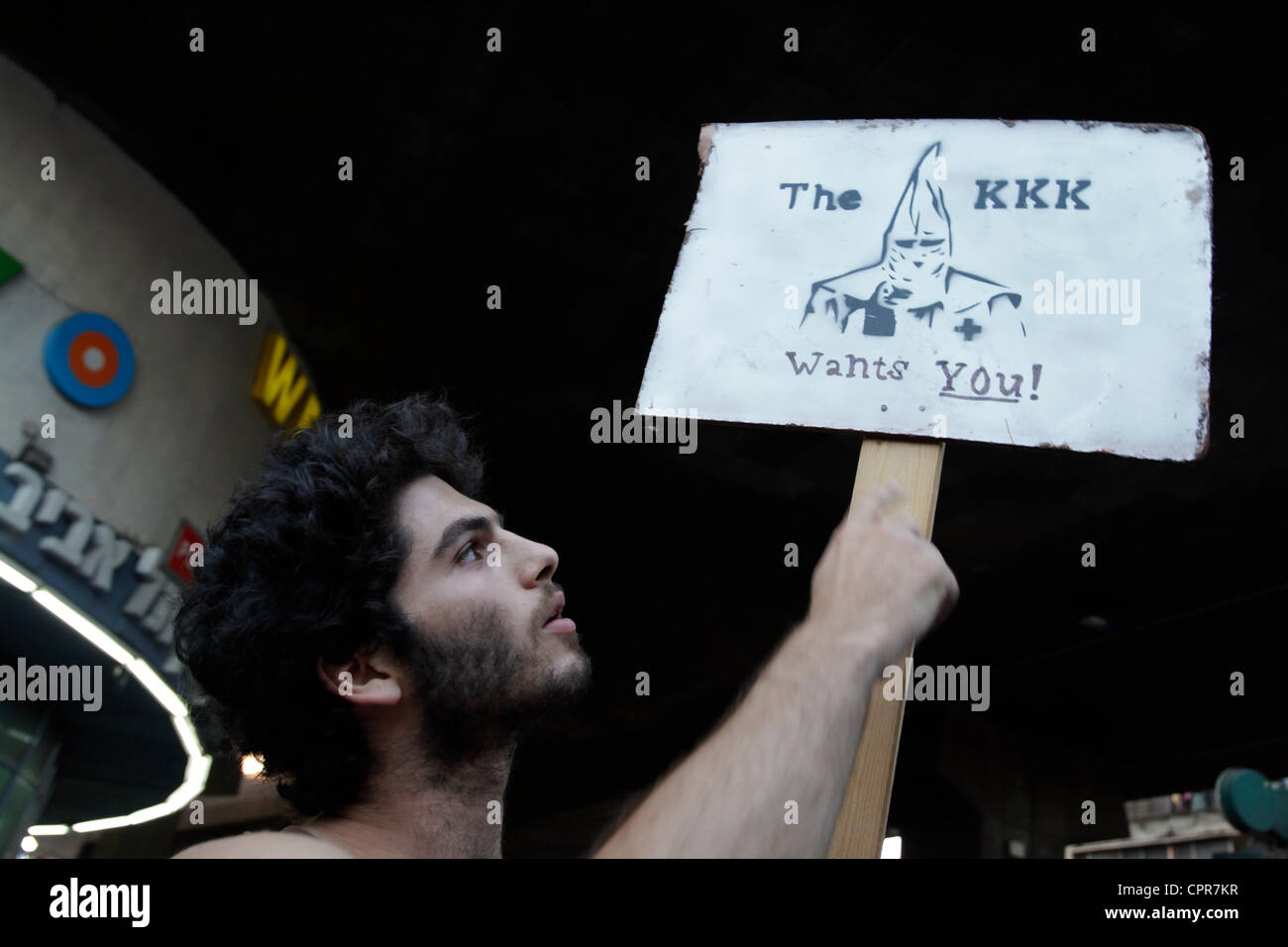 An Israeli Leftist activist holding a placard with the image of a KKK during a counter protest in front of a demonstration organized by Right wing activists against African Migrants in southern Tel Aviv. Israel Stock Photo